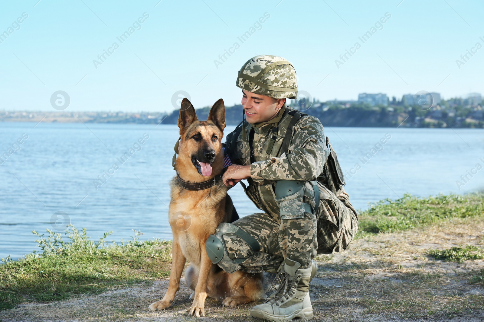 Photo of Man in military uniform with German shepherd dog near river