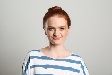 Photo of Candid portrait of happy red haired woman with charming smile on light background