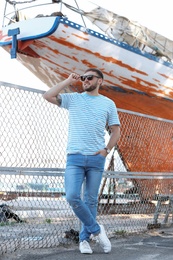 Young hipster man in stylish jeans on pier