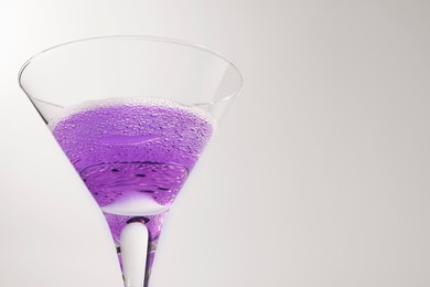 Photo of Fresh cocktail in martini glass on light blue background, closeup. Space for text