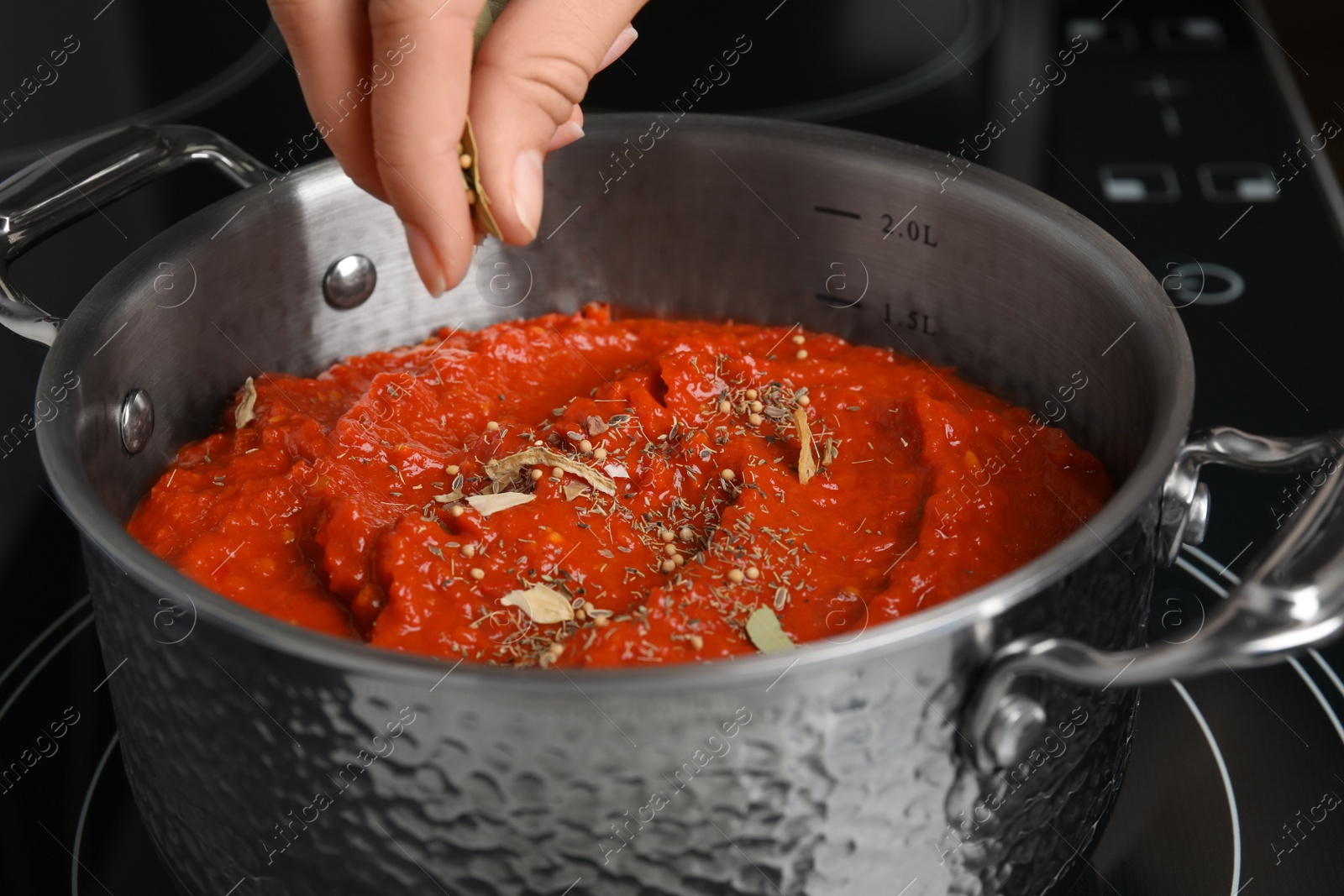 Photo of Woman cooking delicious tomato sauce in pan on stove, closeup