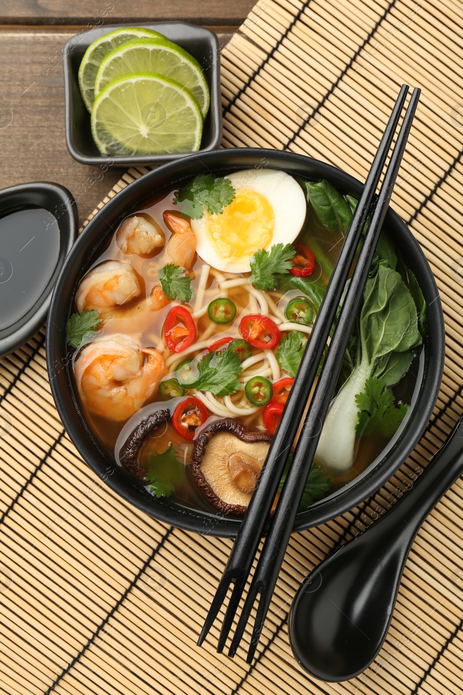 Photo of Delicious ramen with shrimps and egg in bowl served on table, flat lay