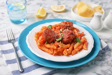 Delicious pasta with meatballs and tomato sauce on table