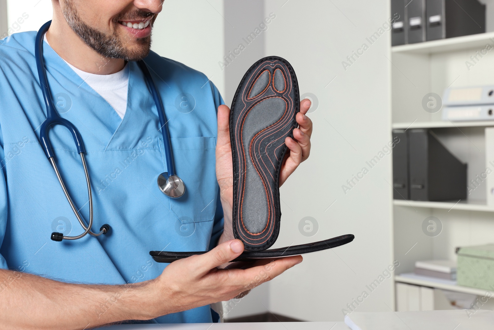 Photo of Male orthopedist showing insoles in hospital, closeup