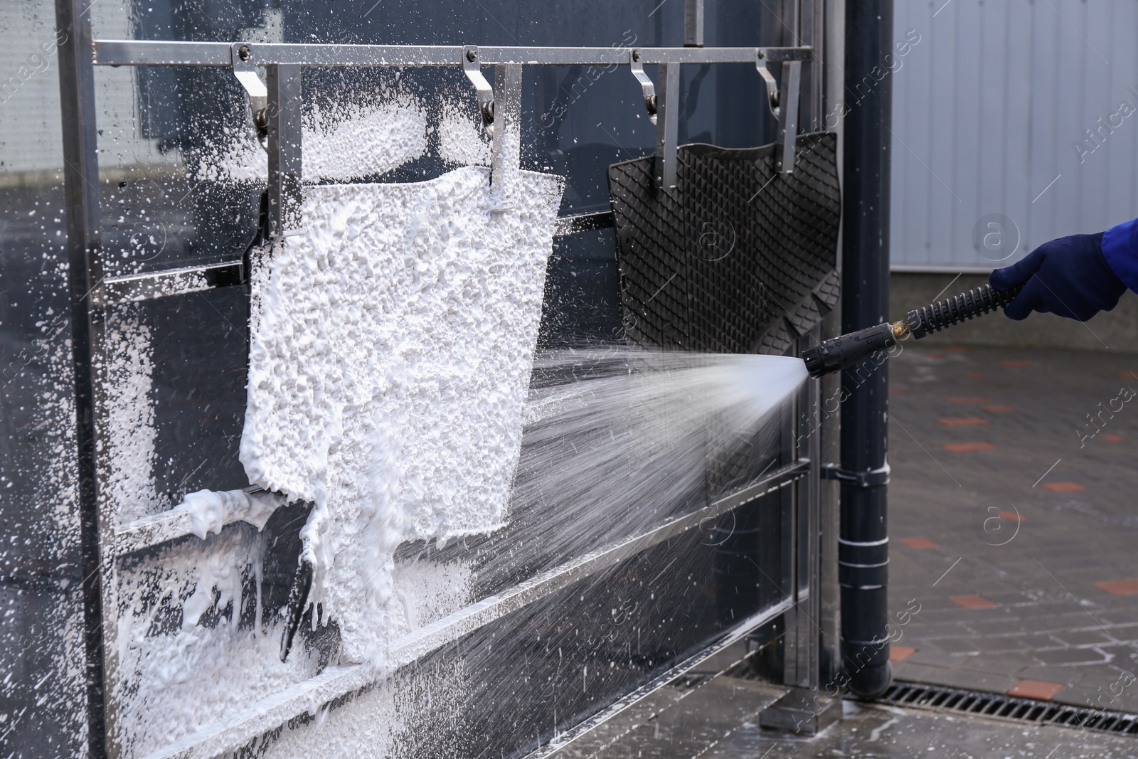 Photo of Cleaning automobile floor mats with high pressure water jet at car wash