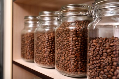Photo of Glass jars with coffee beans on rack, space for text