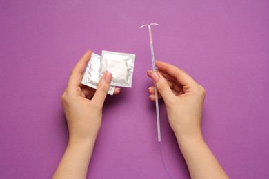 Photo of Woman with condoms and intrauterine device on violet background, top view. Choosing birth control method