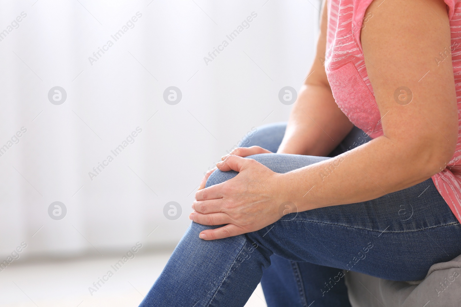 Photo of Senior woman suffering from knee pain at home, closeup. Space for text