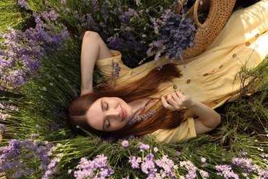Photo of Young woman lying in lavender field on summer day, top view