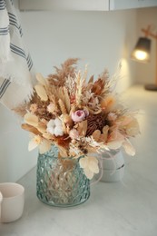 Bouquet of dry flowers and leaves on countertop in kitchen