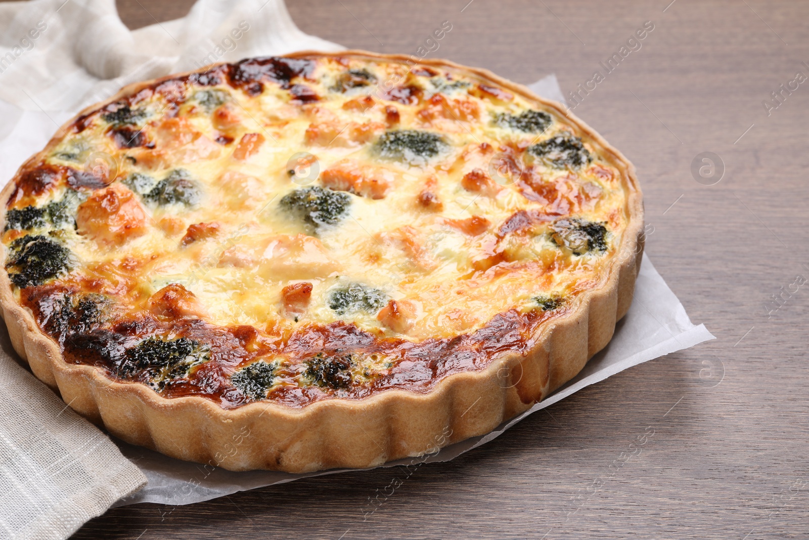 Photo of Delicious homemade quiche with salmon and broccoli on wooden table