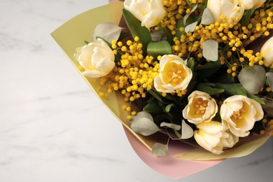 Bouquet of beautiful spring flowers on white marble table, top view. Space for text
