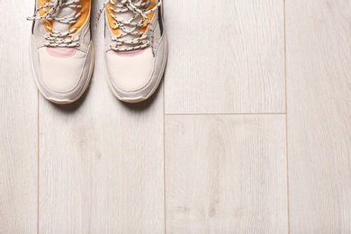 Photo of Pair of sport shoes on wooden floor, top view with space for text