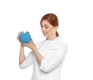 Photo of Portrait of female doctor putting coin into piggy bank on white background