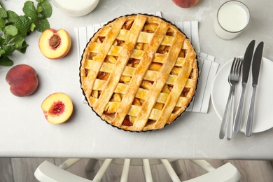 Photo of Delicious fresh peach pie served on light kitchen table, flat lay
