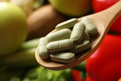 Photo of Dietary supplements. Spoon with pills over food products, closeup