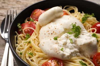 Photo of Delicious spaghetti with burrata cheese and tomatoes in bowl on table, closeup