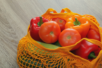 Net bag with vegetables on wooden table