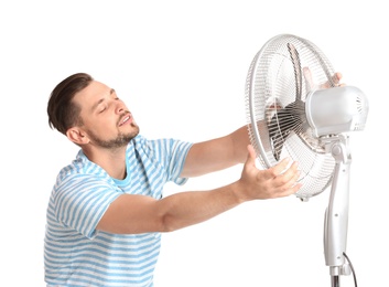 Photo of Man refreshing from heat in front of fan on white background