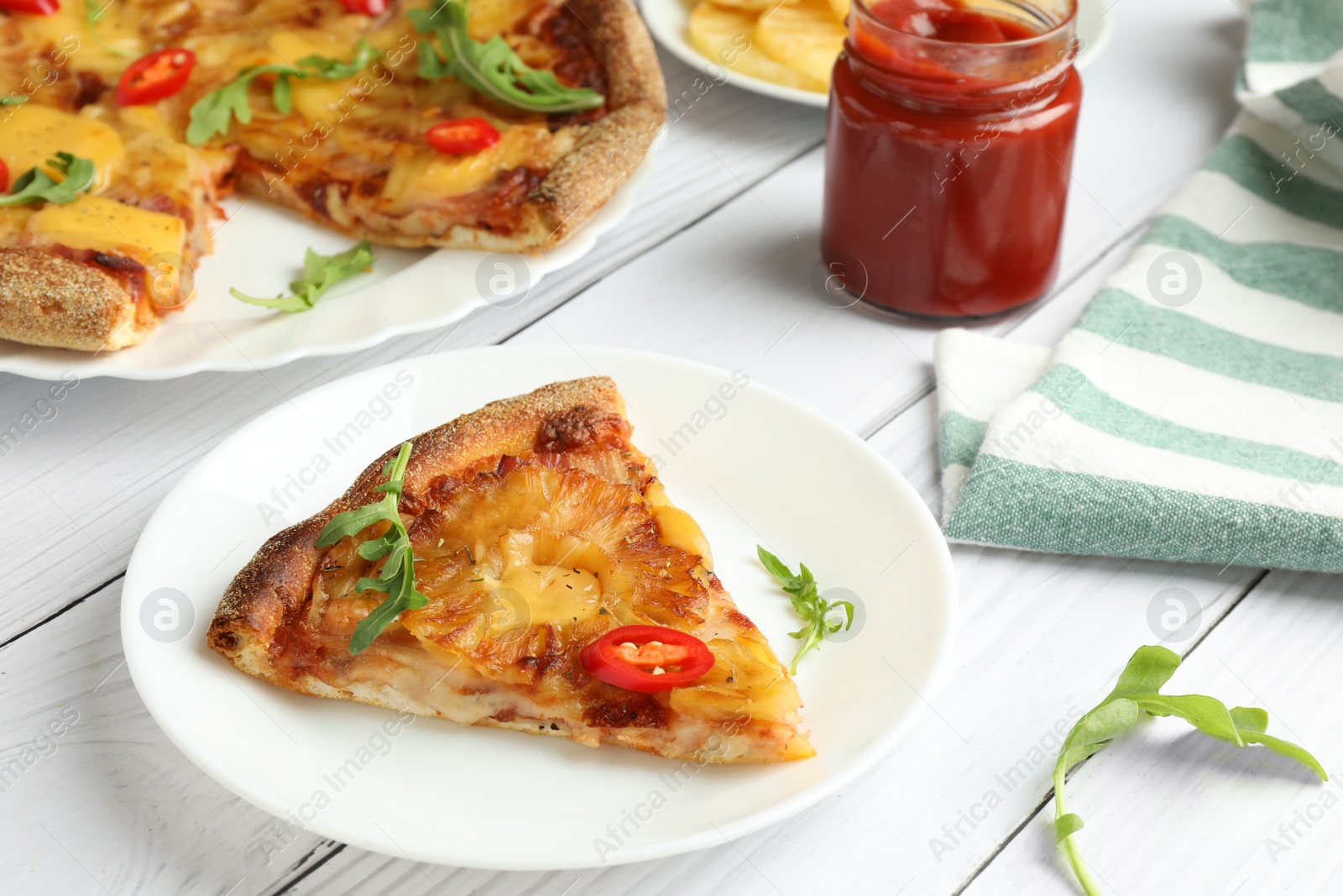 Photo of Plate with piece of delicious pineapple pizza on white wooden table