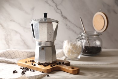 Photo of Moka pot and coffee beans on white wooden table, space for text