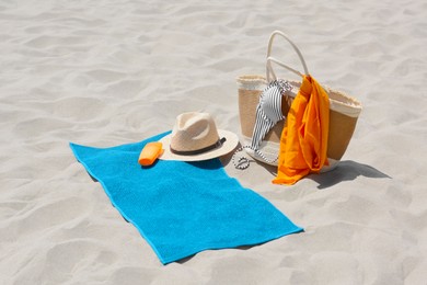 Photo of Blue towel, bag and beach accessories on sand