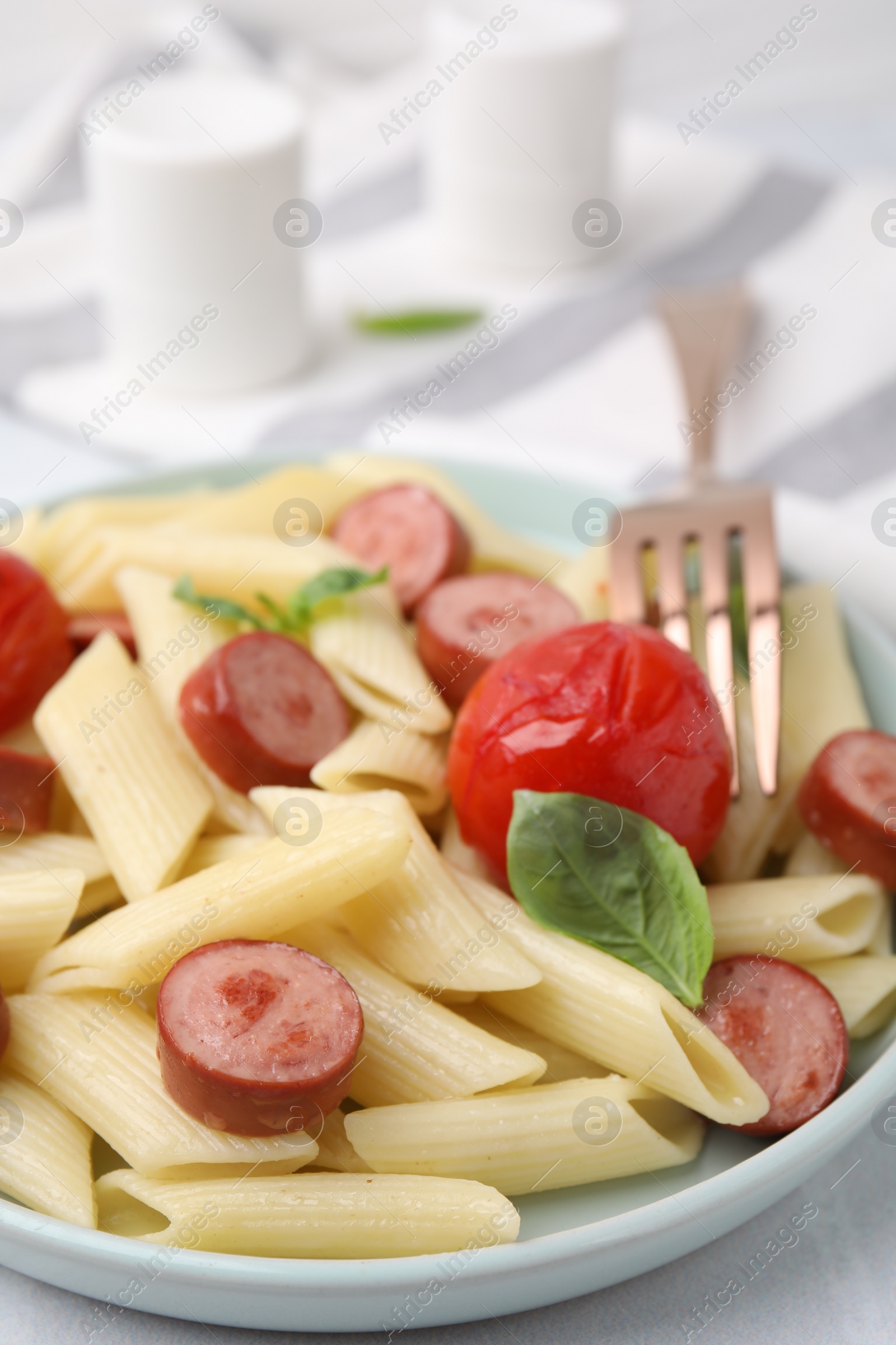 Photo of Tasty pasta with smoked sausage, tomato and basil on table, closeup. Space for text