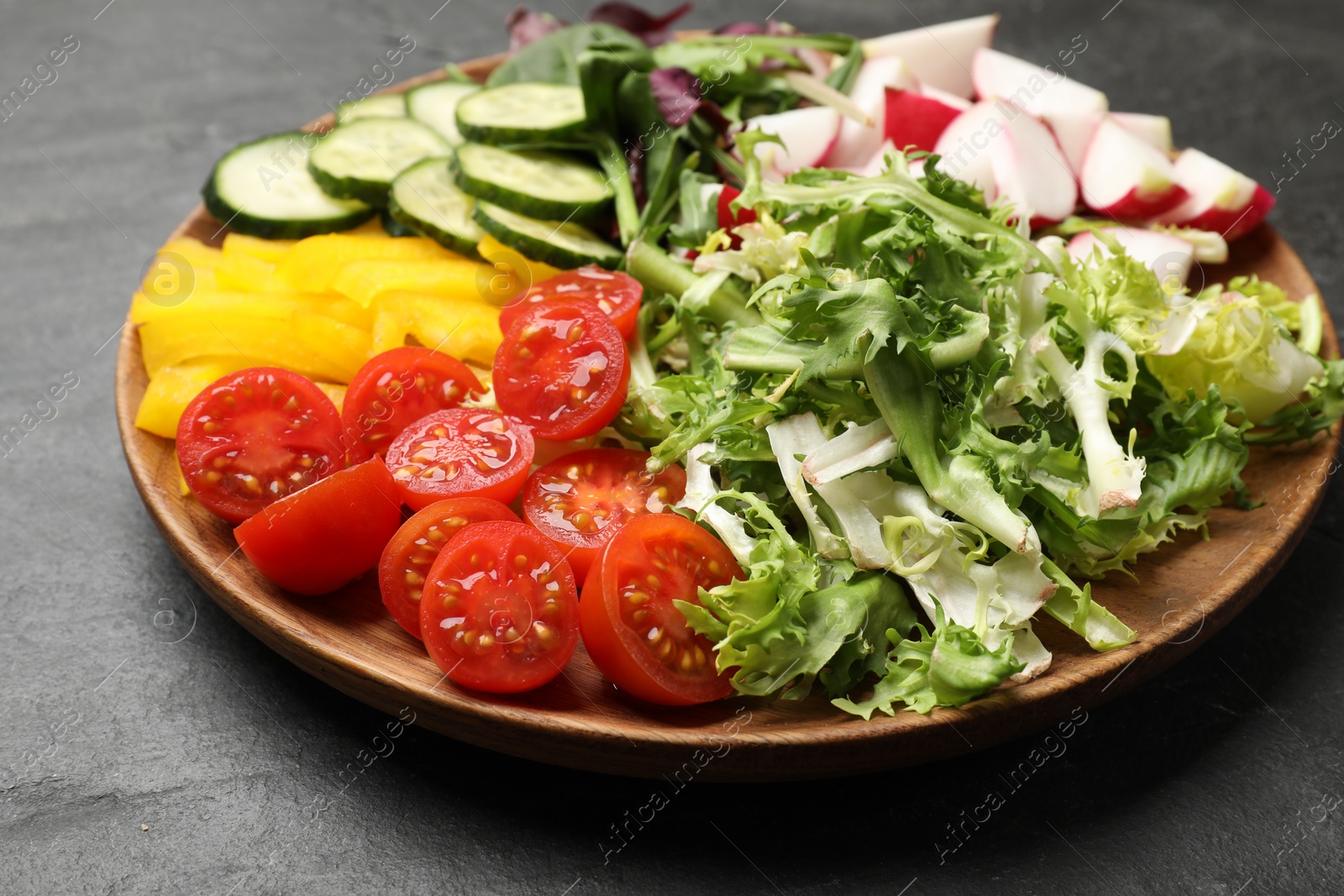 Photo of Vegetarian diet. Plate with tasty vegetables on black table, closeup