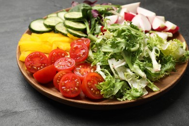 Photo of Vegetarian diet. Plate with tasty vegetables on black table, closeup