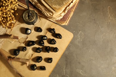 Photo of Many black rune stones, dried flowers and old books on grey table, flat lay. Space for text