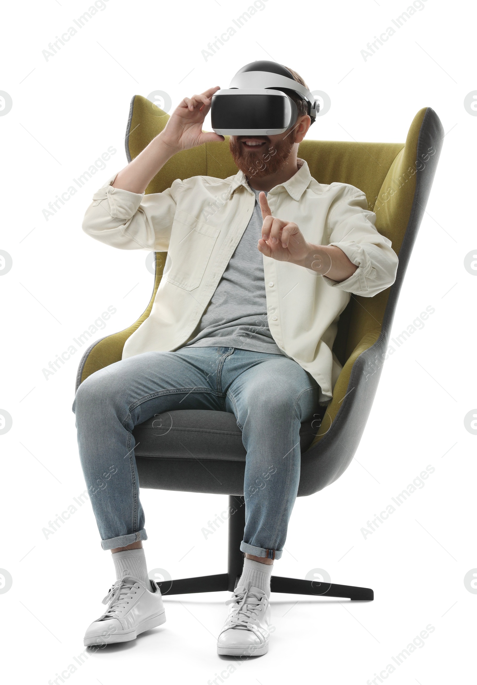 Photo of Man using virtual reality headset while sitting in armchair on white background