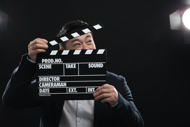 Photo of Asian actor with clapperboard on stage, space for text. Film industry