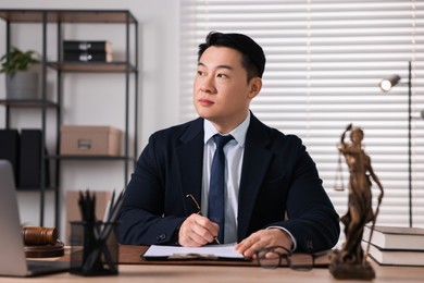 Notary writing notes at wooden table in office