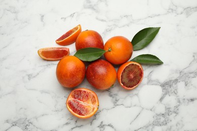 Photo of Many ripe sicilian oranges and leaves on white marble table, flat lay
