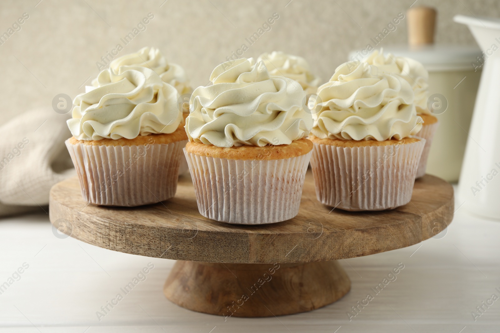 Photo of Tasty vanilla cupcakes with cream on white wooden table