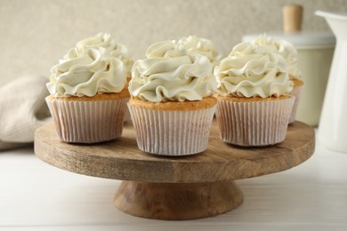 Tasty vanilla cupcakes with cream on white wooden table