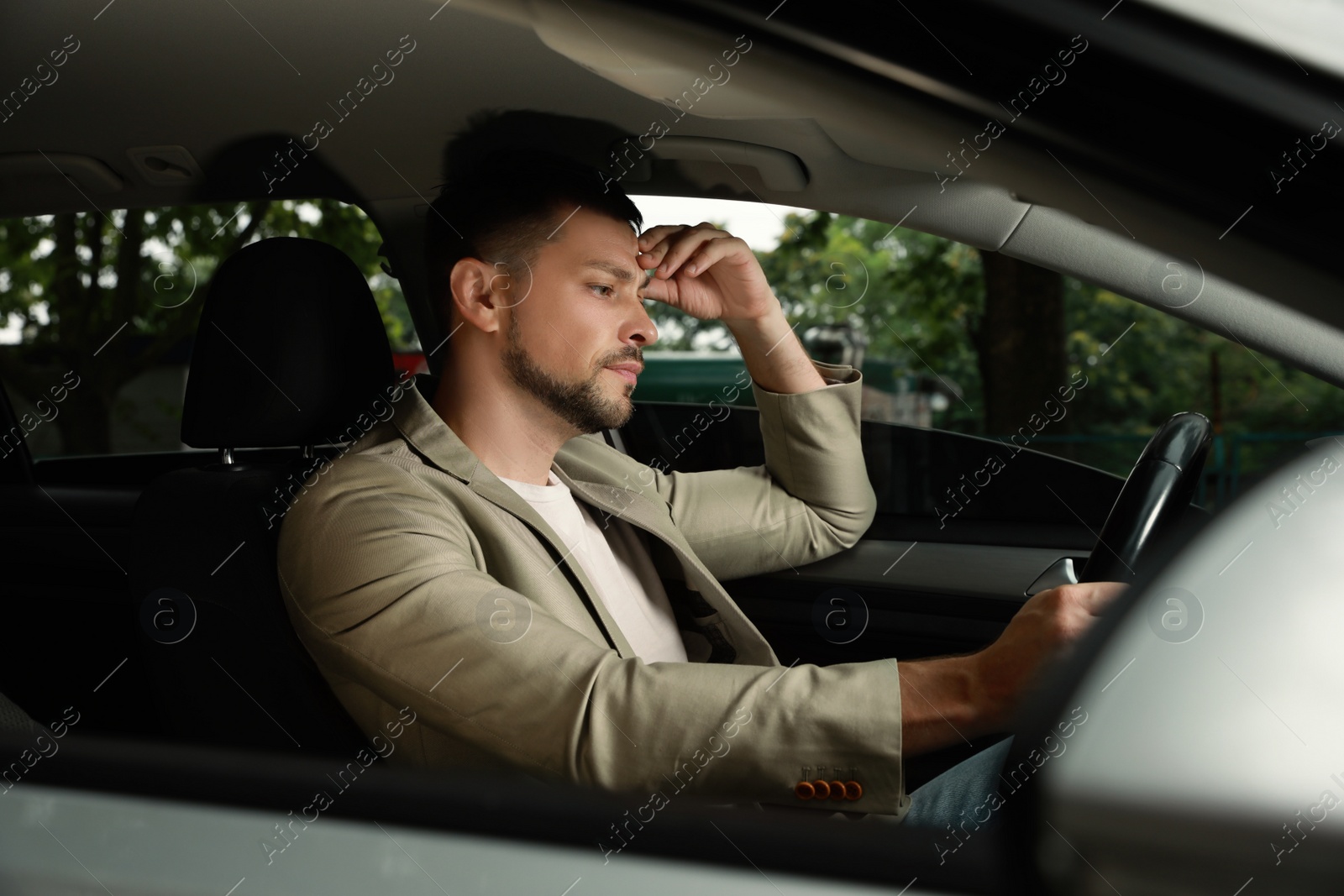 Photo of Stressed businessman in driver's seat of modern car