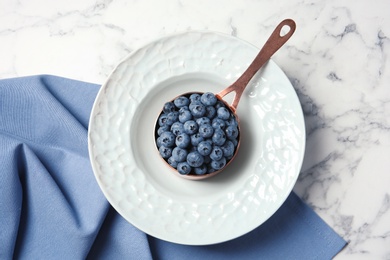 Photo of Dishware with juicy and fresh blueberries on marble table, top view