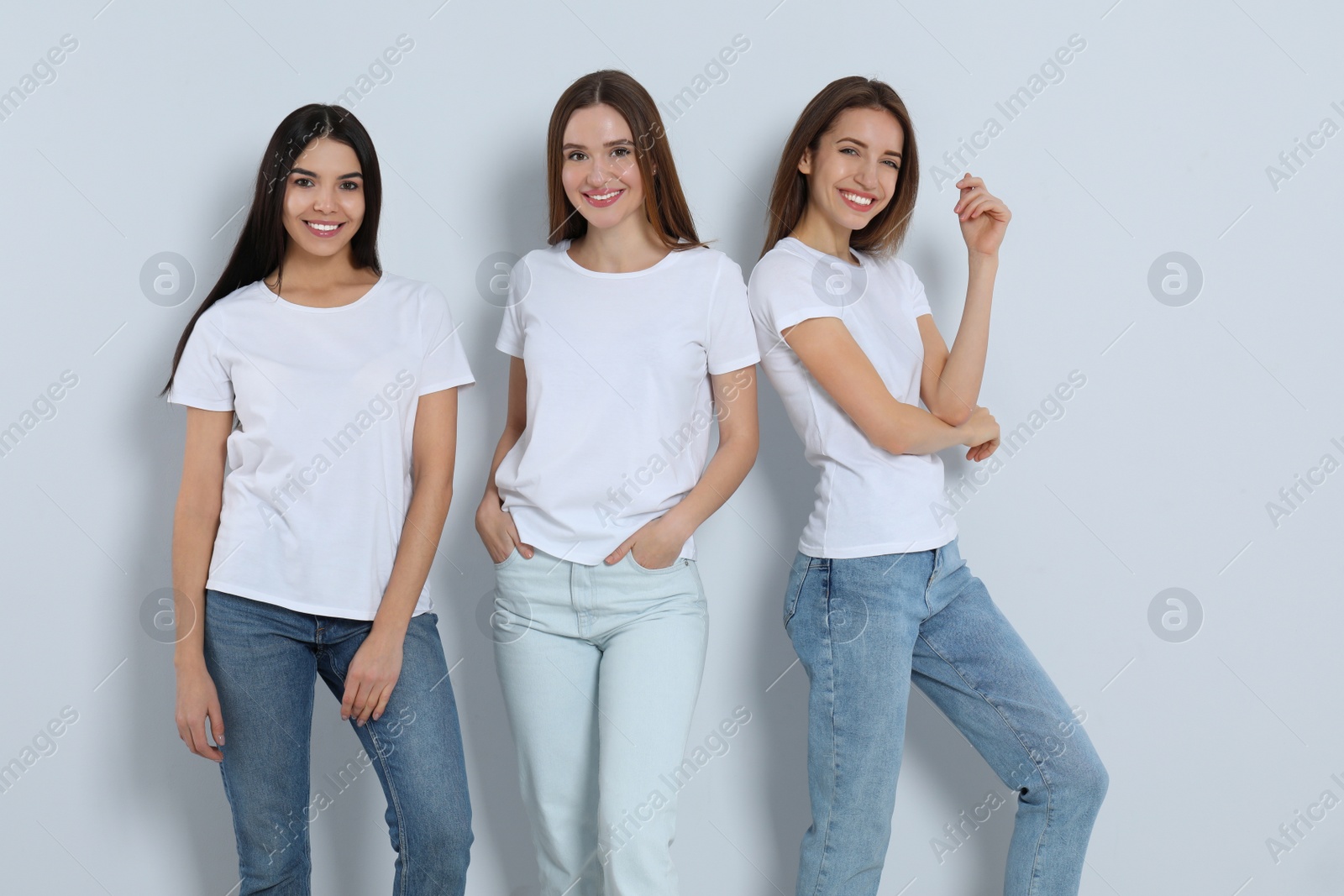 Photo of Group of young women in stylish jeans on light background