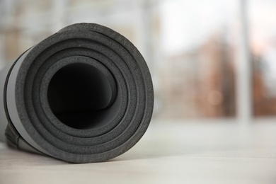 Rolled grey yoga mat on floor indoors