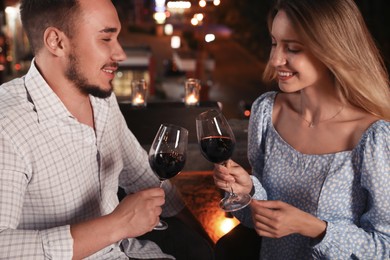 Photo of Romantic couple with glasses of red wine on cafe terrace at night