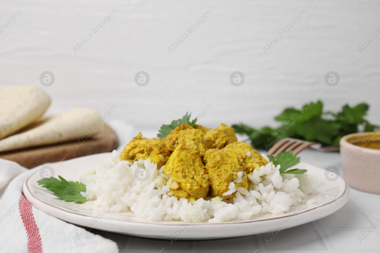 Photo of Delicious rice and chicken with curry sauce on white tiled table, closeup