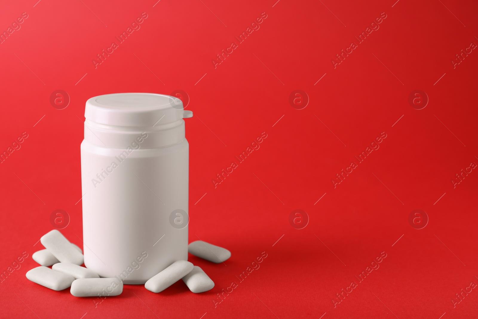 Photo of Jar with chewing gums on red background