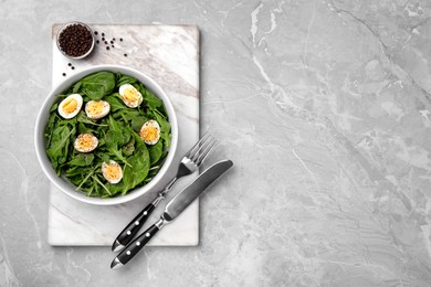 Delicious salad with boiled eggs and herbs served on light grey marble table, top view. Space for text