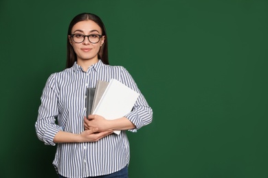 Photo of Portrait of young teacher with notebooks on green background. Space for text