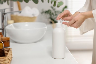 Young woman using body cream in bathroom, closeup