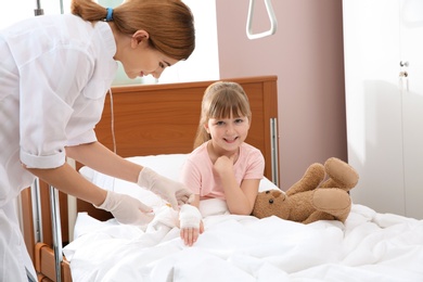 Doctor adjusting intravenous drip for little child in hospital