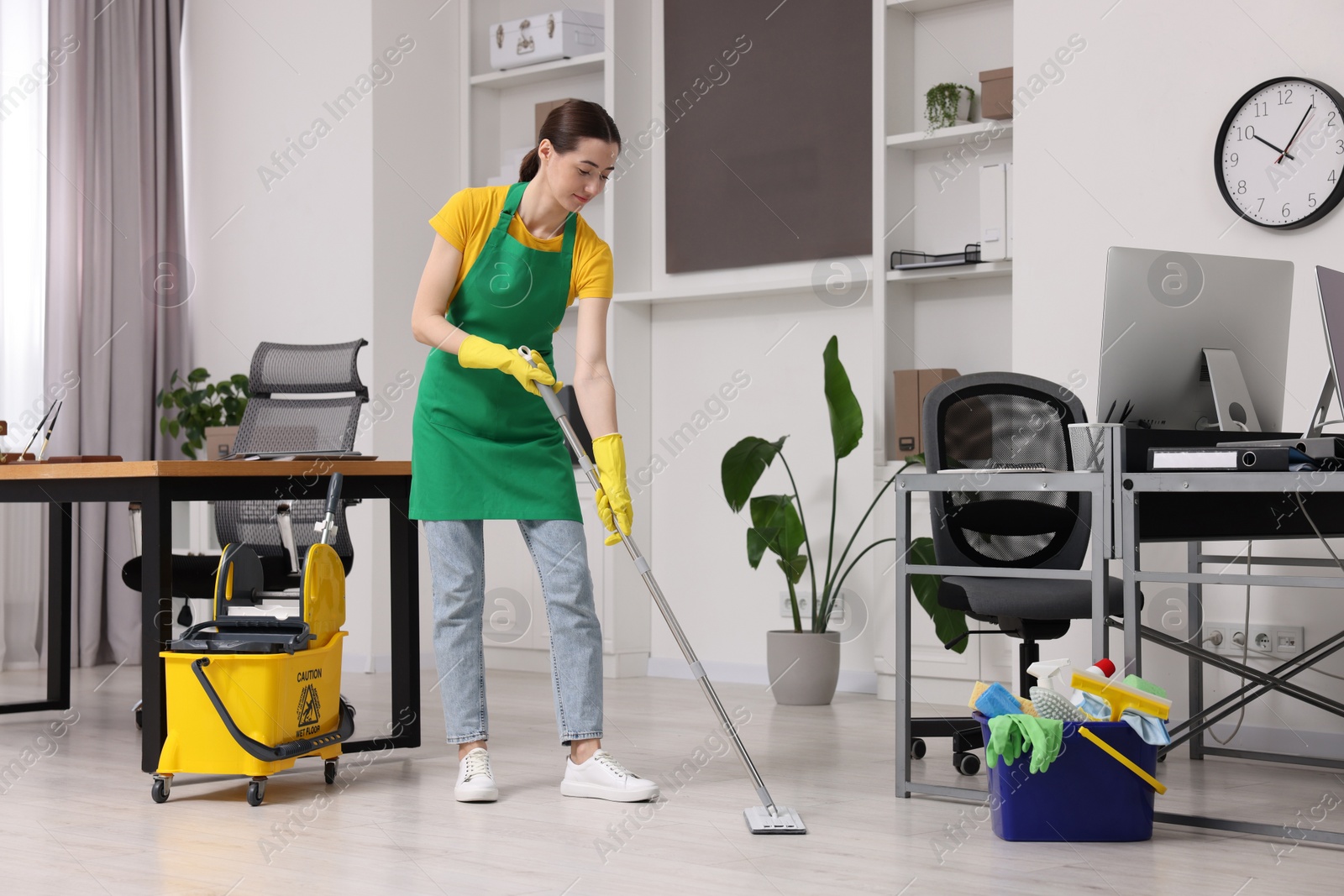 Photo of Cleaning service worker washing floor with mop. Bucket with supplies in office