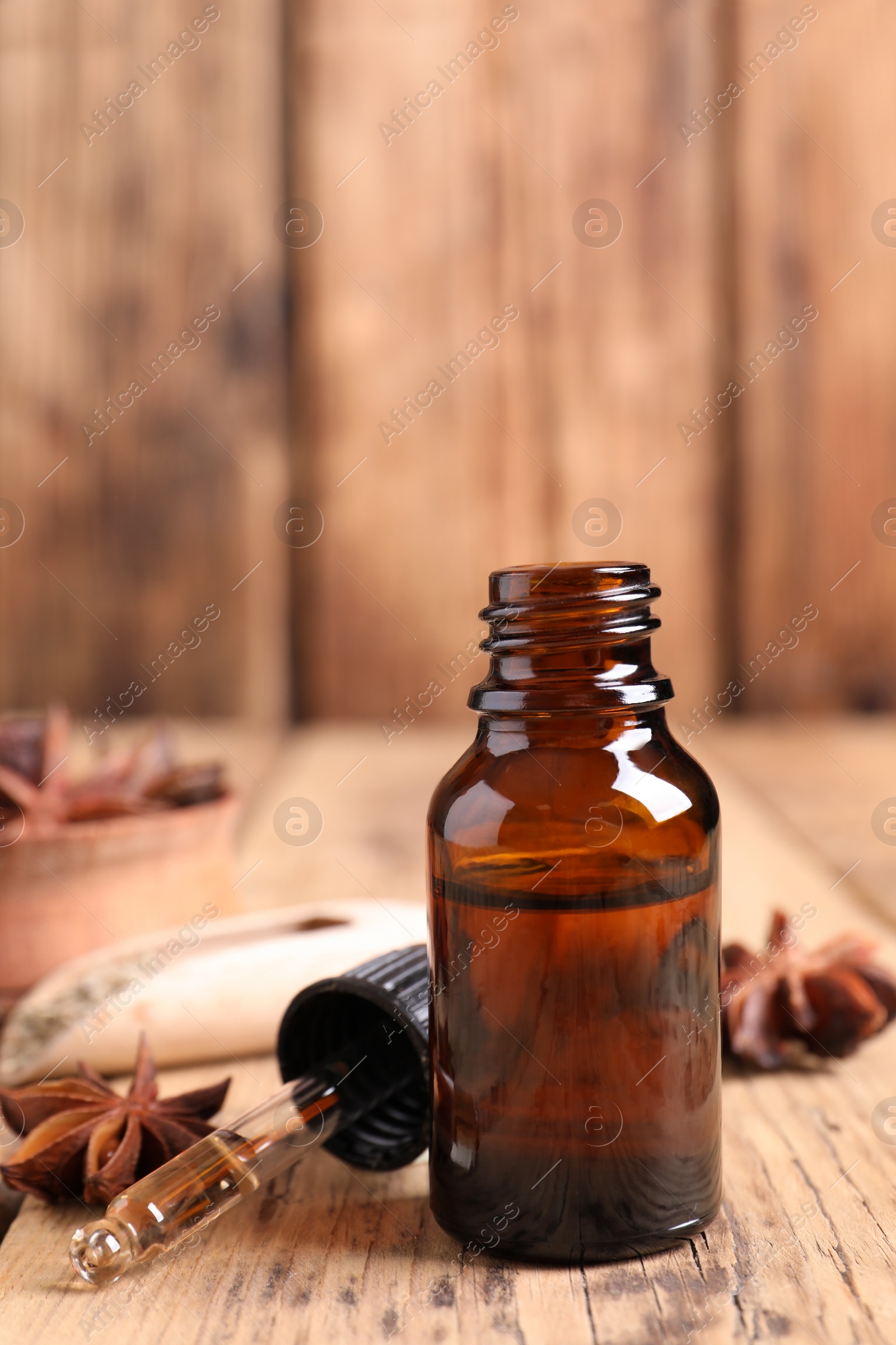 Photo of Bottle of essential oil, dropper and anise on wooden table
