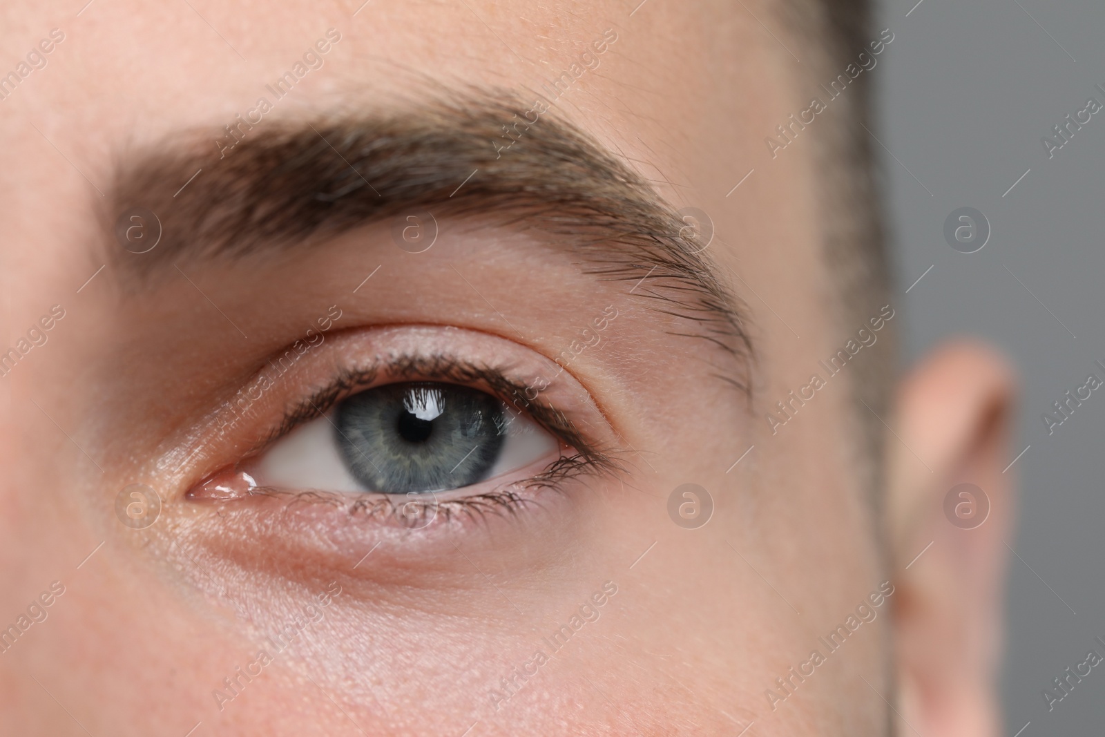 Photo of Closeup view of young man with beautiful eyes on grey background